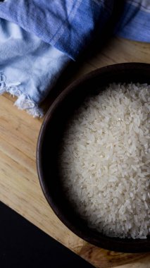 Kil kasede pişmemiş pirinç. Ahşap bir masada, siyah arka planda..