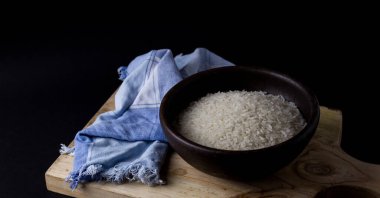 Kil kasede pişmemiş pirinç. Ahşap bir masada, siyah arka planda..