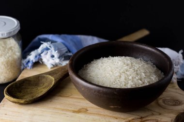 Kil kasede pişmemiş pirinç. Ahşap bir masada, siyah arka planda..