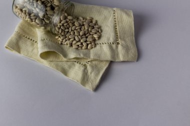 Kumaş peçetedeki cam kavanozda fasulye. Beyaz arka plan. Üst görünüm