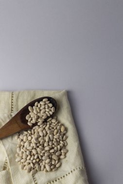 Bez peçete ve tahta kaşıkta fasulye. Beyaz arka plan. Üst görünüm