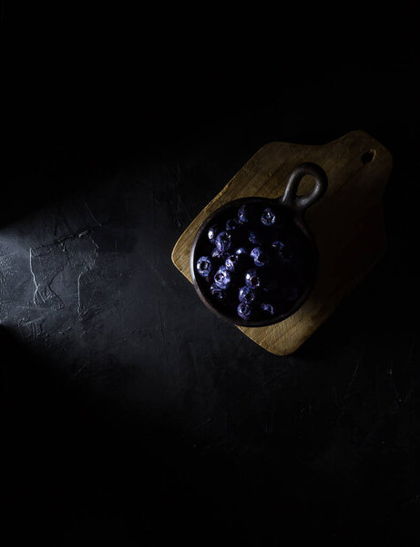 Blueberries in a clay pot with dark background. Dark food concept. Copy Space. Top view