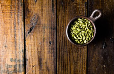 Güzel bir ahşap arka planı olan bir çömleğin içindeki tohumlar. Sağlıklı bir kavram. Vegan Kavramı. Uzayı kopyala Üst görünüm