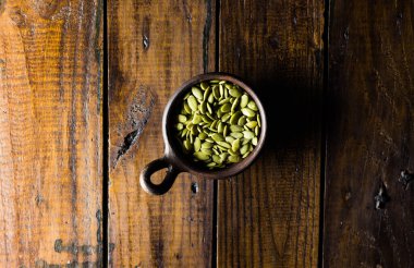 Güzel bir ahşap arka planı olan bir çömleğin içindeki tohumlar. Sağlıklı bir kavram. Vegan Kavramı. Uzayı kopyala Üst görünüm