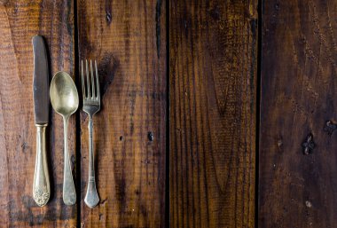 Kırsal ahşap bir masa üzerine çatal bıçak seti. Çatal, kaşık ve bıçak. Yemek konsepti. Boşluğu Kopyala