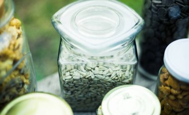 Tohumlar cam kavanozlarda, arka planda, tahta bir masanın üzerinde. Sağlıklı gıda kavramları. Vegan kavramı.