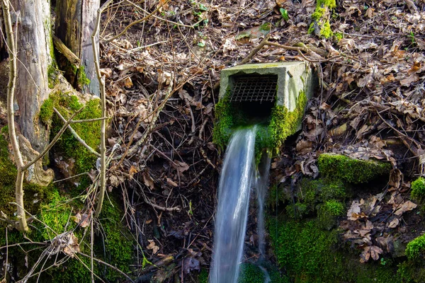 Tubo de drenagem de concreto quadrado o lado de uma encosta com água saindo dela — Fotografia de Stock