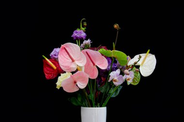 Kırmızı ve beyaz Flamingo çiçekleri, menekşe rengi Lisianthus veya Eustoma, Orkide çiçekli renkli çiçek buketi ve siyah arka planda izole edilmiş eğreltiotu sarılmış.