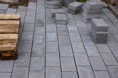 Bir binanın yanına beton kaldırım blokları döşenmiş, bazı kaldırım taşları ileride kullanmak üzere istiflenmiştir