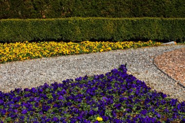 Metal kenarlı bir üçgen oluşturarak bir parkta farklı renkte çakıl, mavi ve sarı hanım evlatlarını ayırıyor.