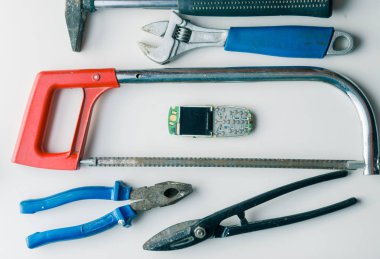 kırık cep telefonu tamir için yanlış araçları ile beyaz masa üzerinde. eğlenceli bir konsept
