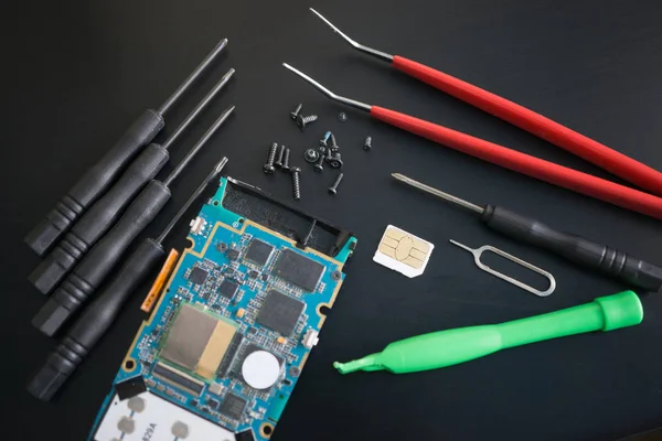 Top view shot of a disassembled smartphone and lot of tools for repair — Stock Photo, Image