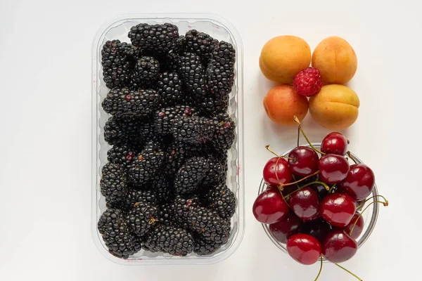 Mora fresca sabrosa, cereza y albaricoques en una bandeja transparente de plástico —  Fotos de Stock