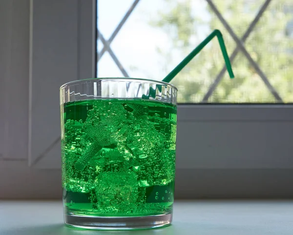glass with green soda aerated water