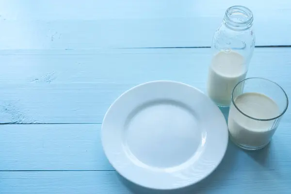 Serving of empty white plate, bottle and glass of milk — Stock Photo, Image