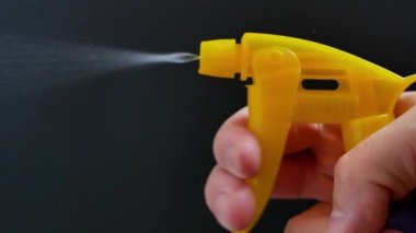 Eline su püskürtücü serpiştirilmiş. Siyah arka planda deterjan serpiştirilmiş. ev aletleri, yüzey ya da pencere temizleme reklam konsepti. 4k Uhd video kaydı