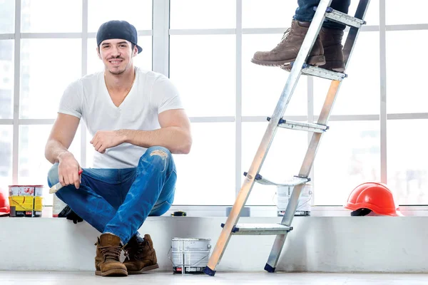 Moving in and repairs in the apartment. Young worker guy sitting