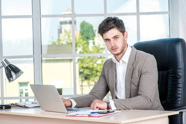 Confident businessman sitting in the office and working on laptop. Businessman making successful business.