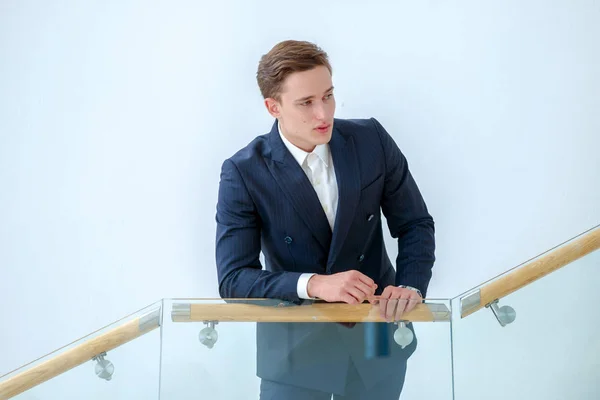 Search client. Successful businessman standing on stairs in the business office and looking ahead. Businessman in formal wear.