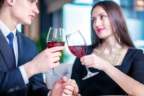 Enamored a festive dinner for two. Romantic dinner in the restaurant. Young loving couple visits a restaurant and raised their glasses of wine close-up view