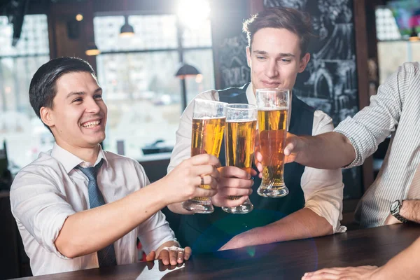 Relax after work. Three cheerful friends met at the bar and clin