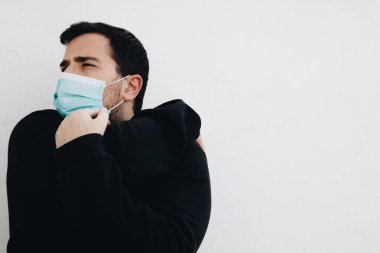 Adam tıbbi bir maskeyle egzersiz yapmadan önce kollarını uzatıyor.