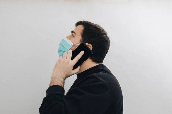 Adam telefonuyla ve tıbbi maskesiyle konuşuyor..