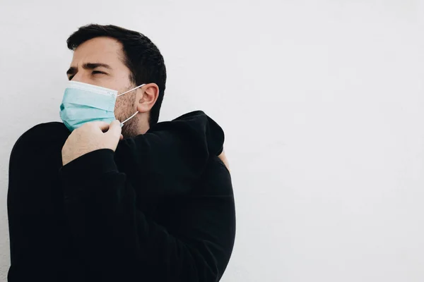 Adam tıbbi bir maskeyle egzersiz yapmadan önce kollarını uzatıyor.