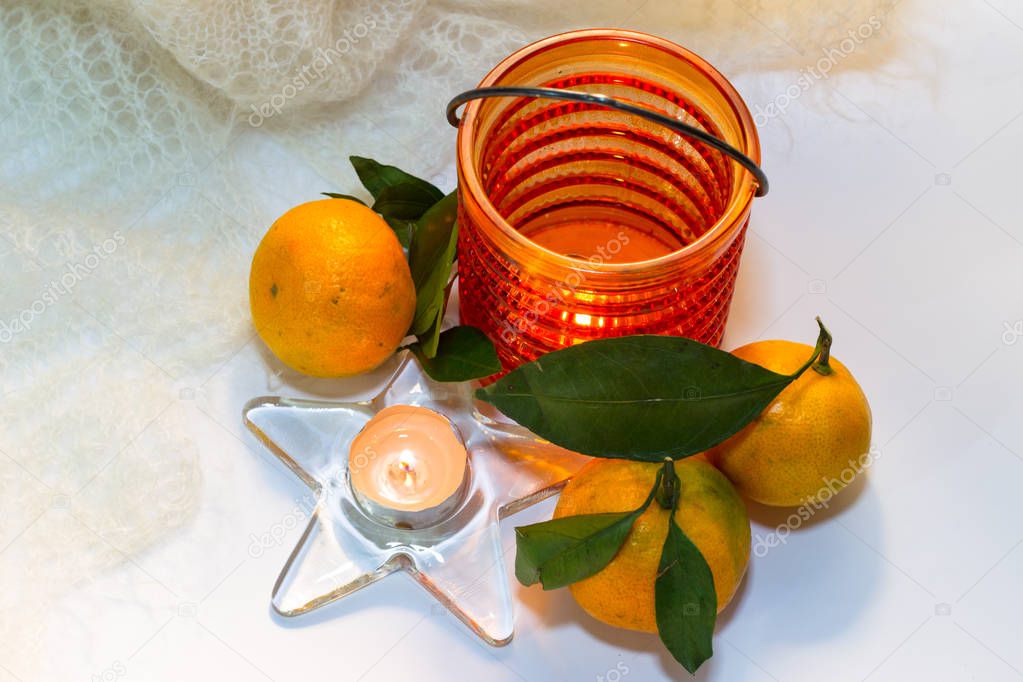 Still life with tangerines, feather shawl and a candle in a cand
