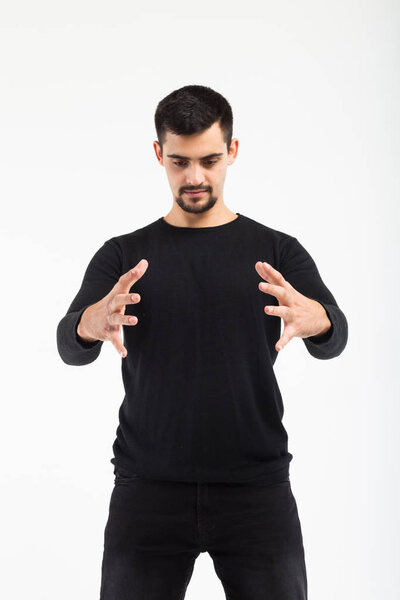 A young man holds his hands, as if holding an invisible ball in 