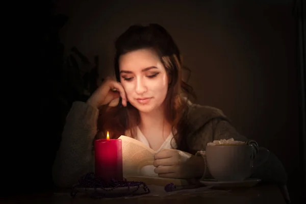 Das Mädchen liest das Buch mit einer Kerze, einer roten Kerze, einem retro ima — Stockfoto