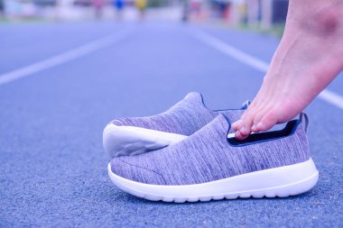 Bir adam koşu pistinde gri spor ayakkabıları giyiyor. Spor.