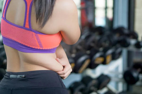 Close up woman holding excessive fat belly at fitness gym. Diet,