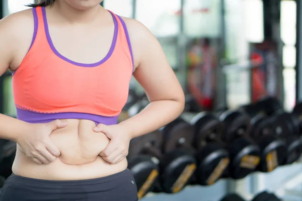 Close up woman holding excessive fat belly at fitness gym. Diet,