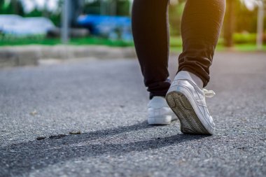 Bahçe parkında genç kadın yürüyüşçü bacaklarını kapat. Spor yapıyor.