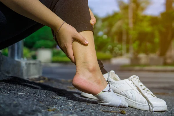 Young woman touching her painful ankle,suffering from ankle inju