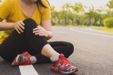 Diz yaralanmaları. Genç sporcu kadın dizini tutuyor. 