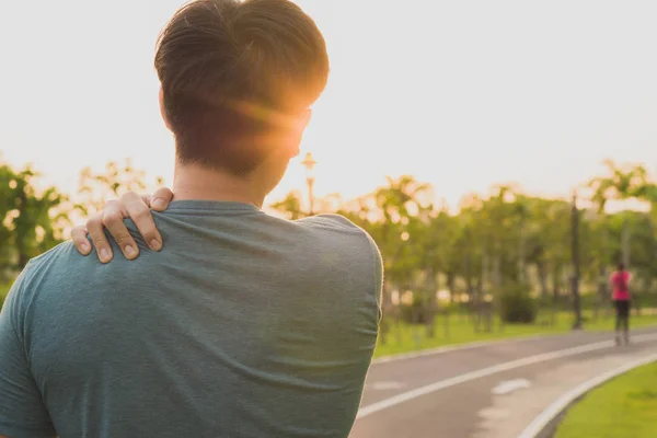 A male athlete suffering from neck pain and injury at the park. — Stock Photo, Image