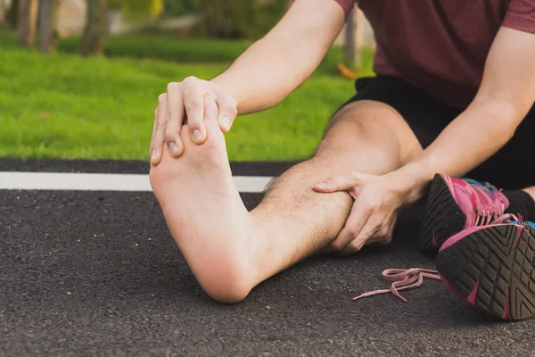 Mladý muž masíruje svou bolavou nohu od běhání a běhání — Stock fotografie
