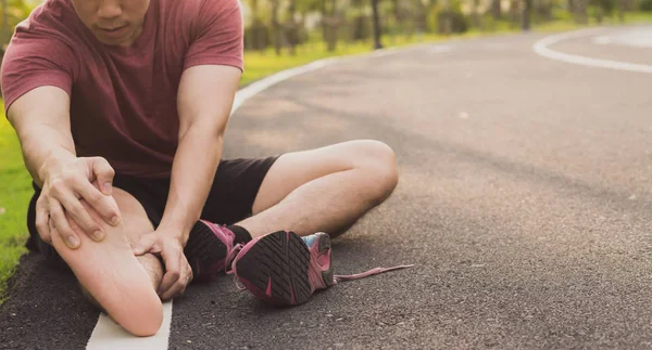 Mladý muž masíruje svou bolavou nohu od běhání a běhání — Stock fotografie