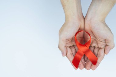 AIDS farkındalığı, kırmızı yardım şeridi tutan erkek elleri. 