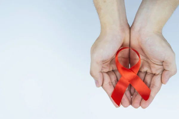 Ayuda a la concienciación, manos masculinas sosteniendo cinta roja de concienciación sobre el SIDA — Foto de Stock