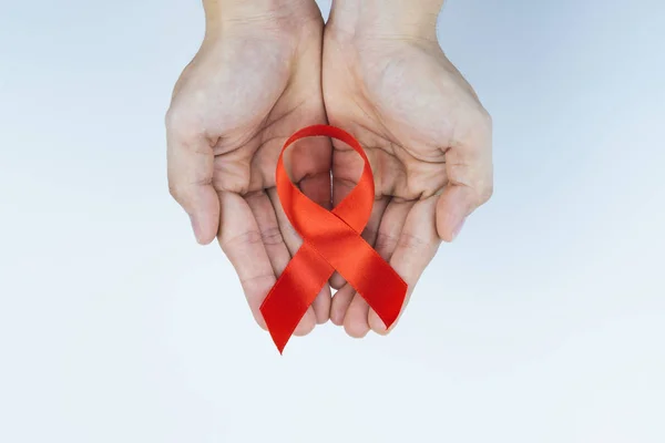 Ayuda a la concienciación, manos masculinas sosteniendo cinta roja de concienciación sobre el SIDA — Foto de Stock