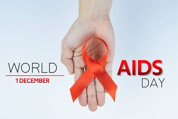 Aids consapevolezza, mani maschili in possesso di nastro rosso di consapevolezza AIDS su — Foto Stock