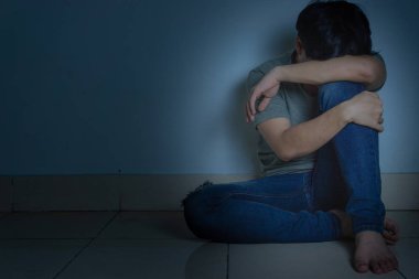 Üzgün adam, karanlık bir odada tek başına otururken dizine sarılıp ağlar. Sefalet