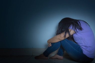 Üzgün kadın, karanlık bir odada tek başına otururken dizine sarılıp ağlar. Dep.