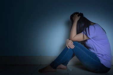 Üzgün kadın, karanlık bir odada tek başına otururken dizine sarılıp ağlar. Dep.