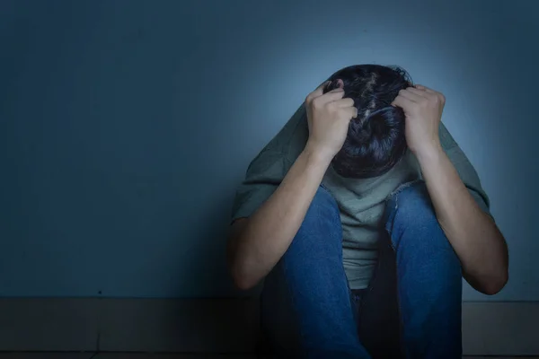 Homem triste abraçar o joelho e chorar sentado sozinho em um quarto escuro. Depre — Fotografia de Stock