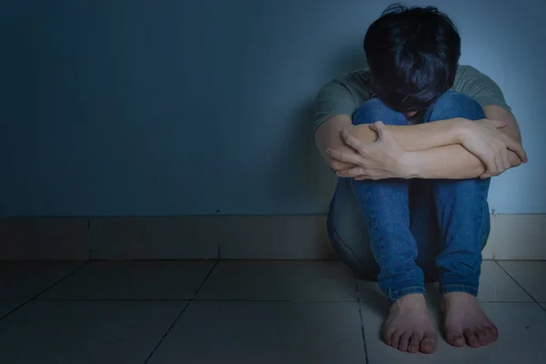 Sad man hug his knee and cry sitting alone in a dark room. Depre — Stock Photo, Image