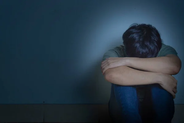 Szomorú ember öleli térdét és sír ül egyedül egy sötét szobában. Előre. — Stock Fotó